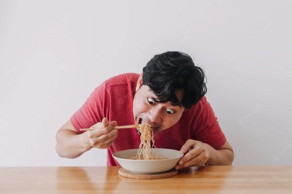 Man eating noodles while slurping